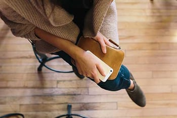picture of a woman looking down at her cell phone and day planner - How can a Sober Coach Help in Addiction Recovery? - Hired Power offers sober coaches, sober companions and recovery assistance services to southern california and across the US