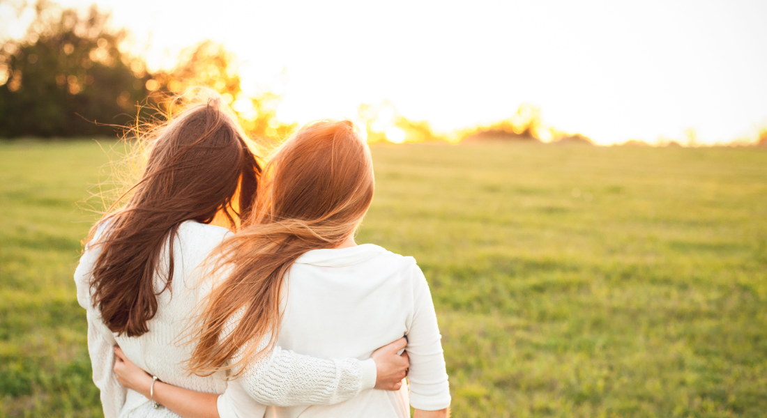 two women arm in arm with their back to the camera