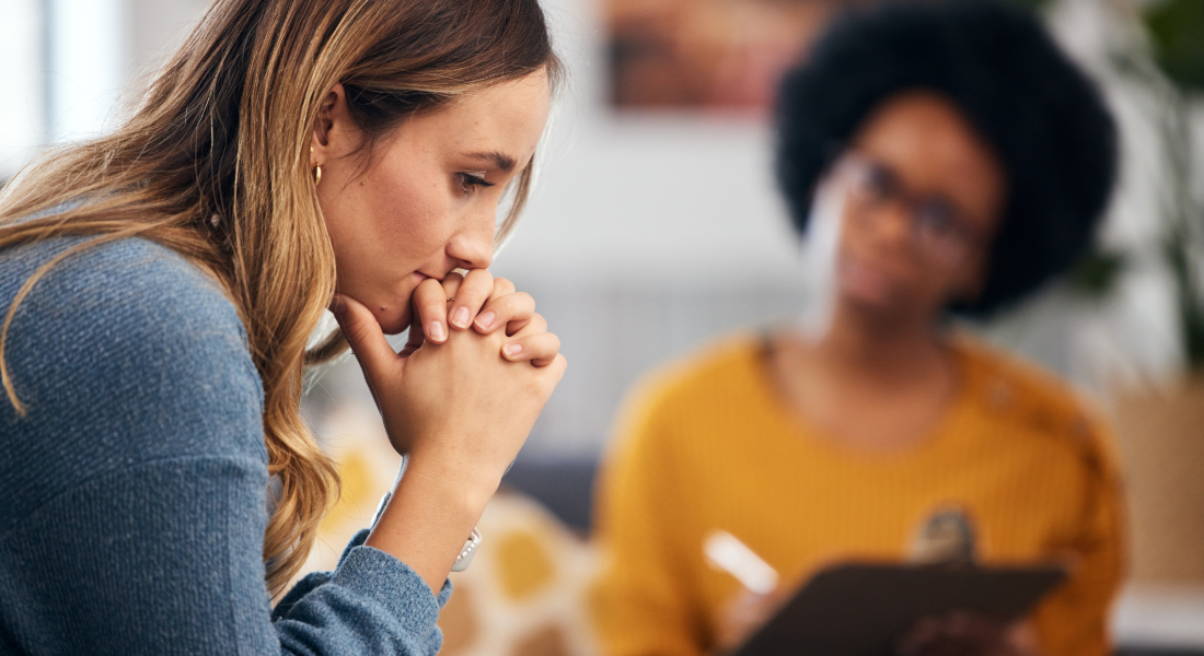 a woman thinking while another woman writes on a clipboard